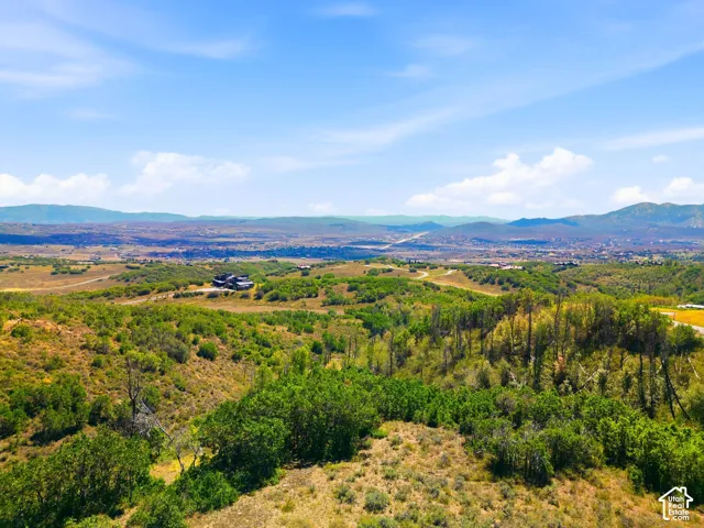Expansive rural landscape with distant mountainous terrain, a clear blue sky, and scattered residences