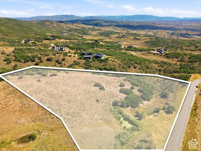 Expansive undeveloped land featuring varied terrain and natural vegetation, bordered by a paved road