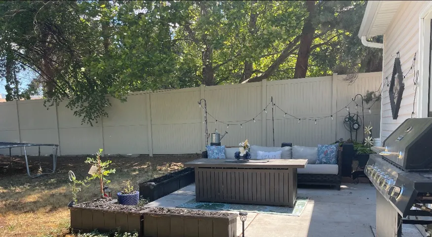 Private fenced yard with a concrete patio, planter boxes, and mature trees