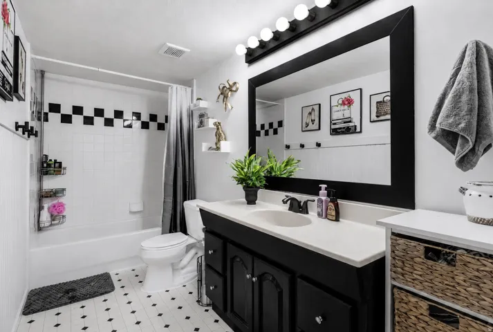 White tile bathtub surround with black accent tiles