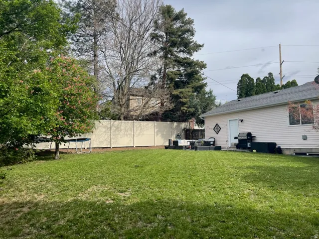 Expansive backyard with a manicured lawn, complete with mature trees and a privacy fence