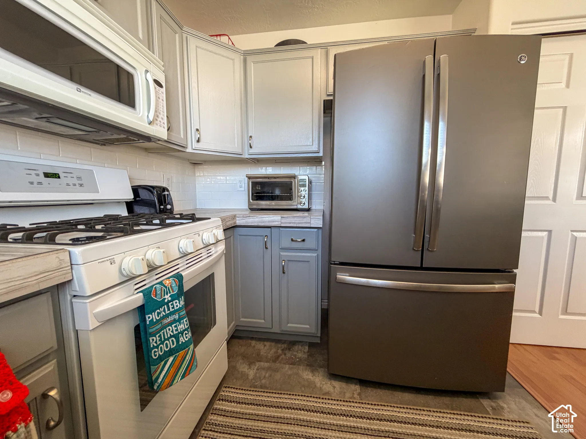 Kitchen featuring gray cabinetry, white subway tile backsplash, a white oven range, and a stainless steel French door refrigerator