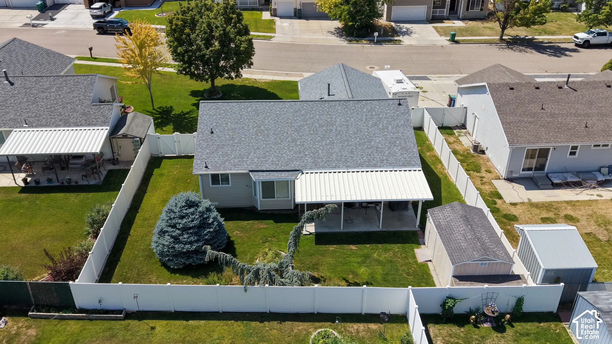 Backyard with a manicured lawn, established landscaping, and perimeter fencing