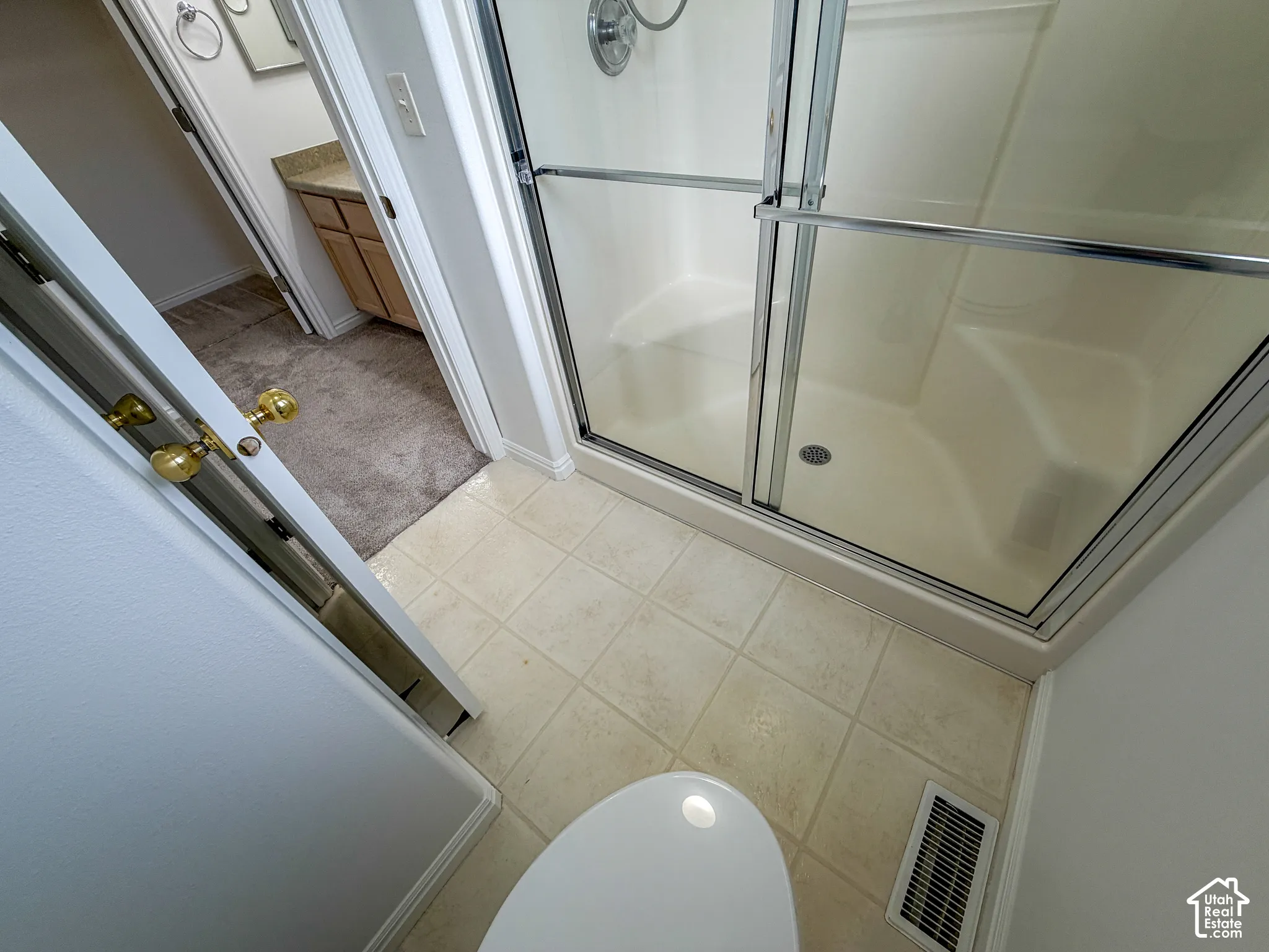 Tile flooring with a walk-in shower featuring a sliding glass door