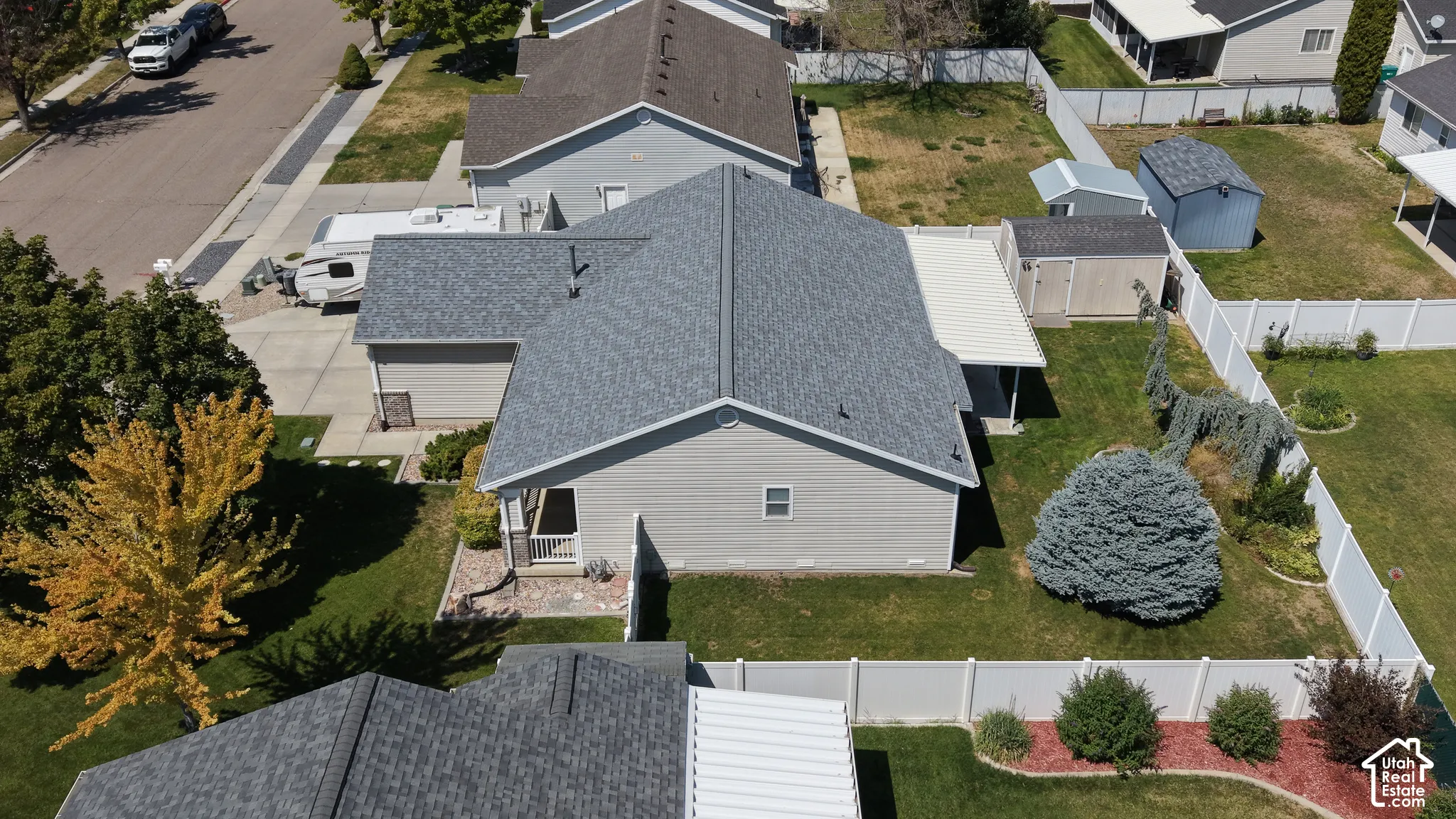 Gable roof with asphalt shingles, vinyl siding, covered patio, fenced yard, and dedicated storage structures
