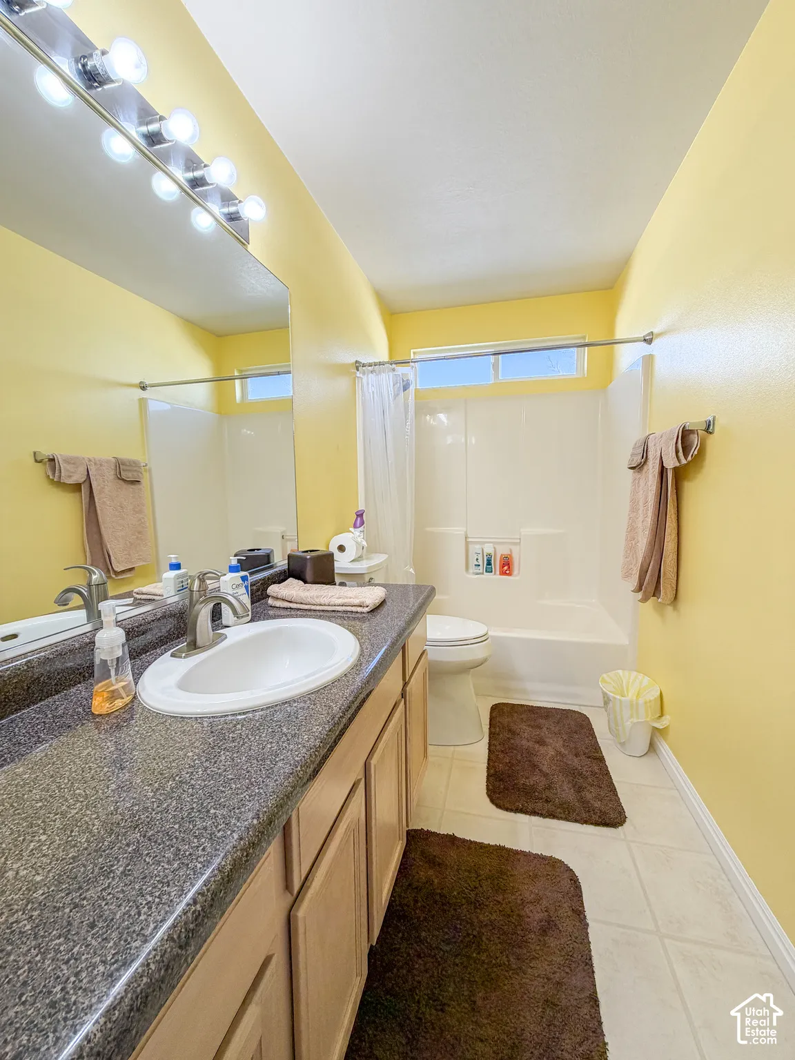 Bathroom featuring a single vanity with an integrated sink, broad mirror, overhead vanity lighting, and built-in shower-tub combination