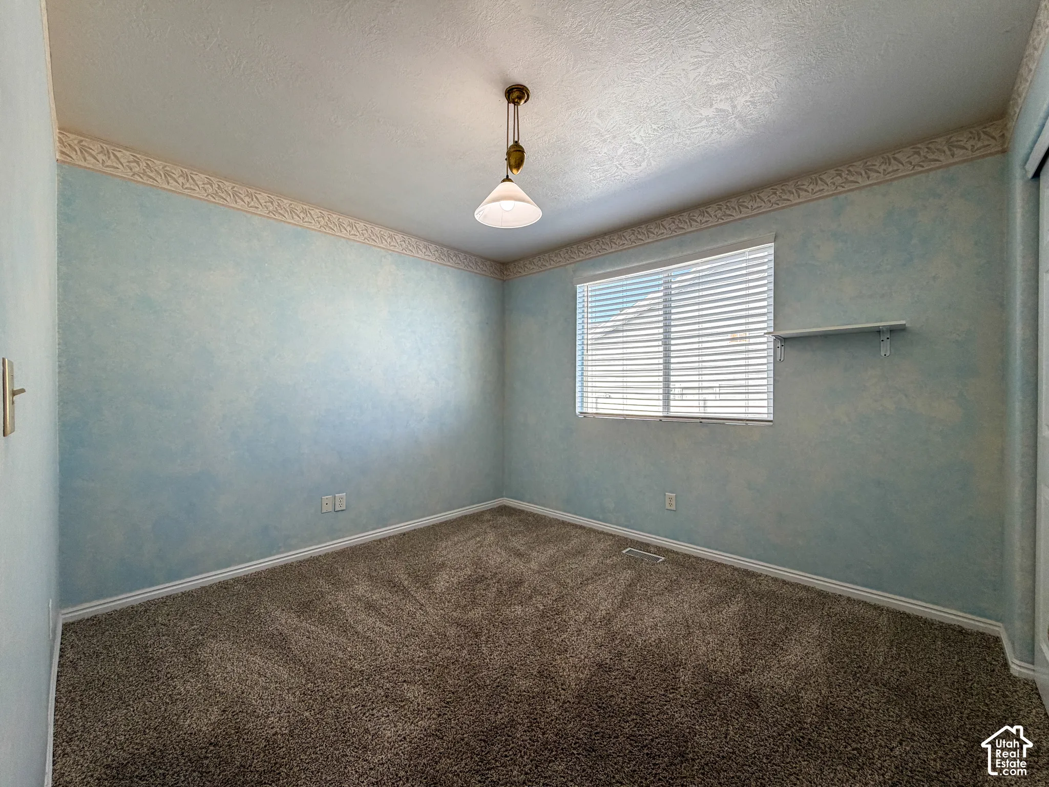 Wall-to-wall carpeting, window with blinds, ceiling-mounted light fixture, and a wall shelf