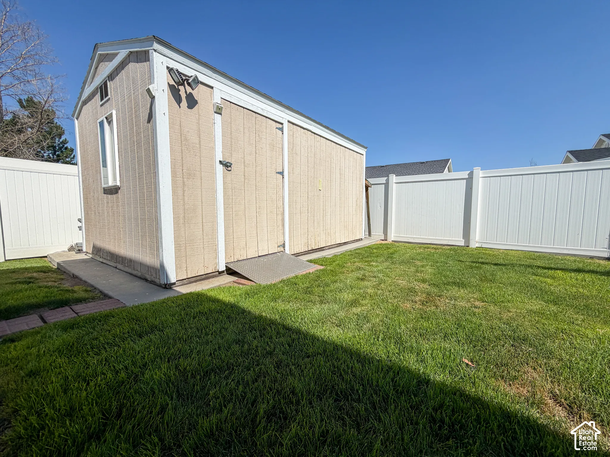 Detached storage shed with a window, concrete foundation, and double entry doors, set within a fenced yard