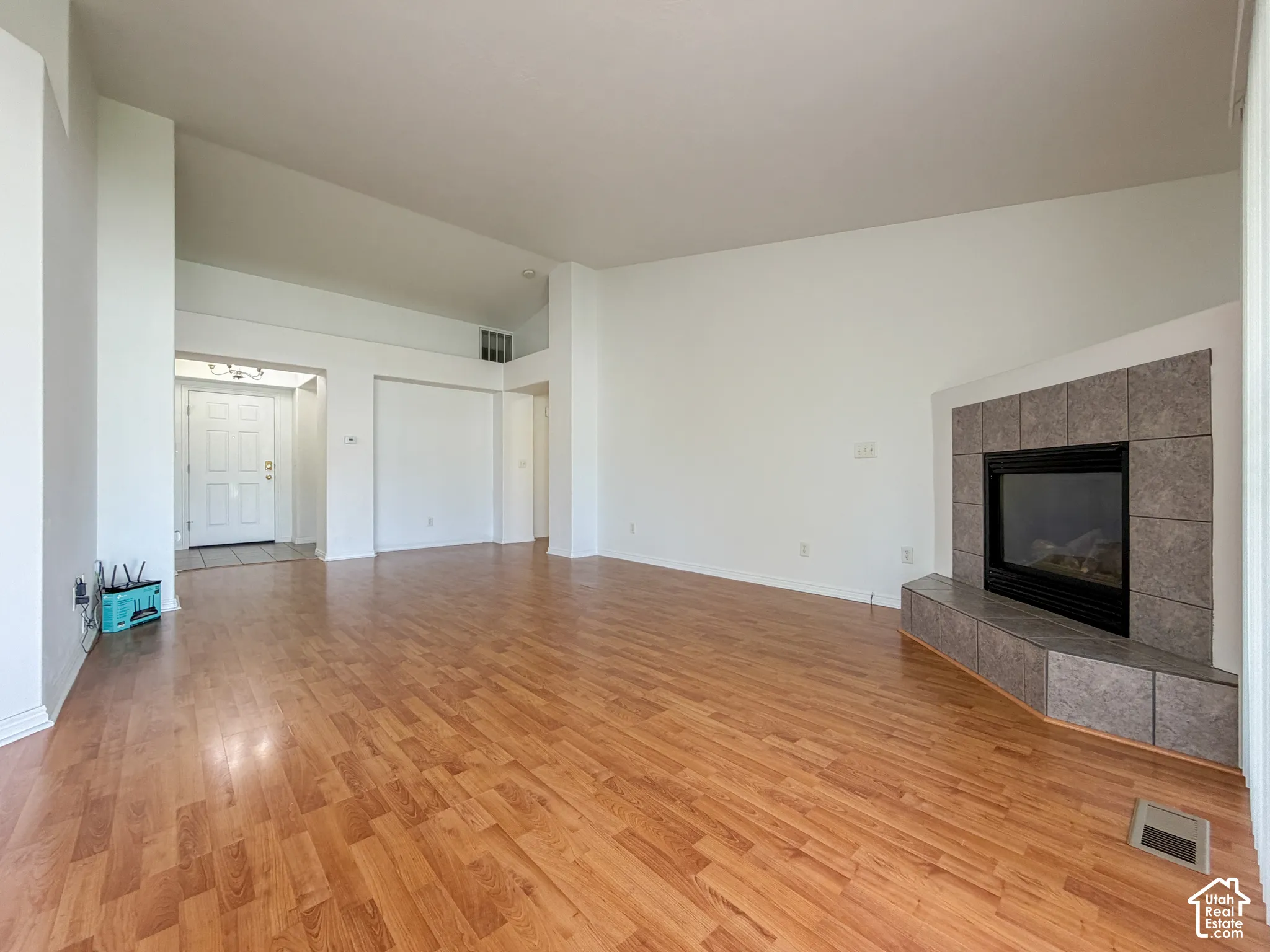 Vaulted ceilings, wood-finish flooring, recessed entry, and a tiled fireplace