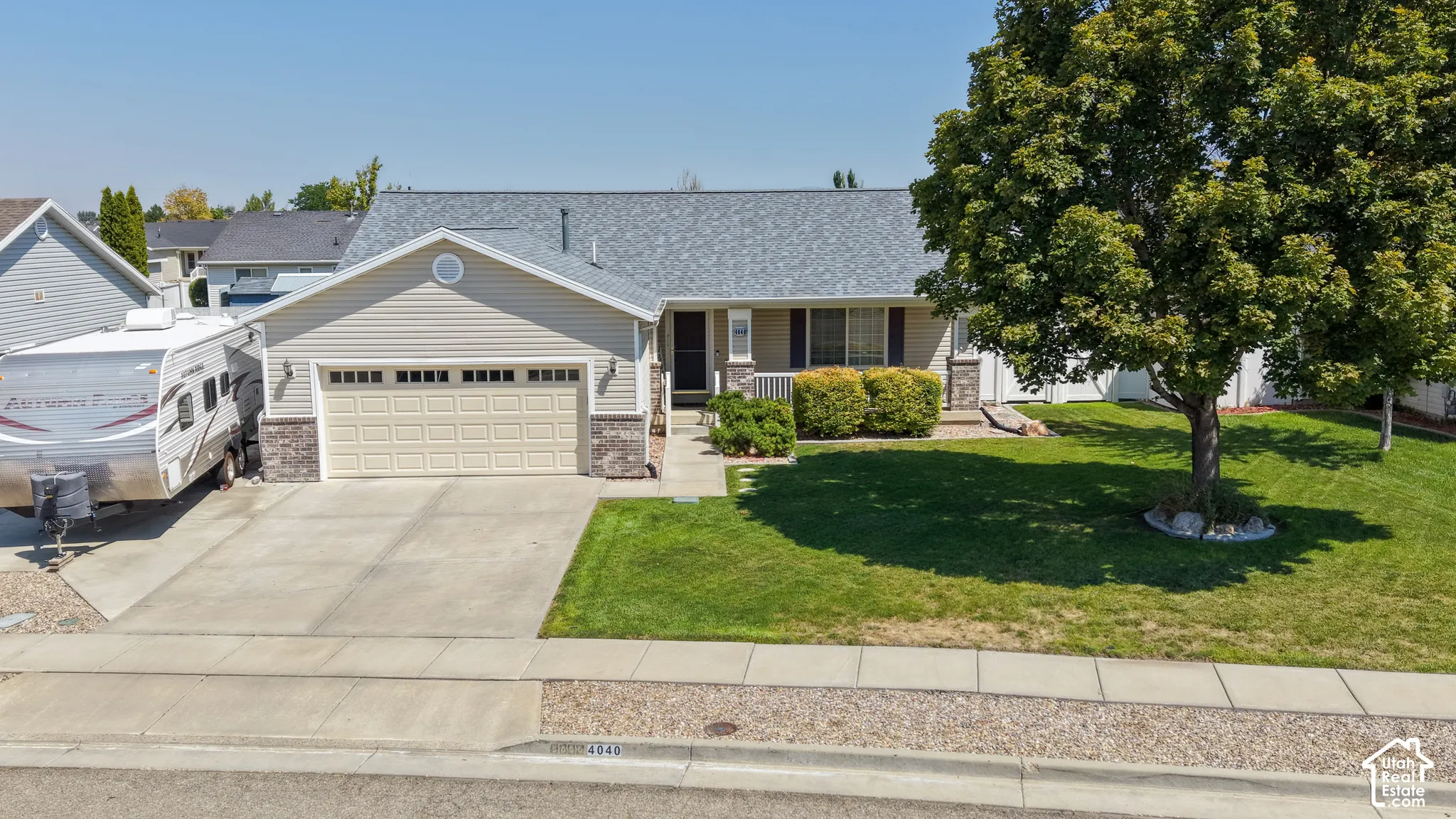 Single-story residence featuring light-colored siding with stone veneer accents, an attached two-car garage, and a concrete driveway