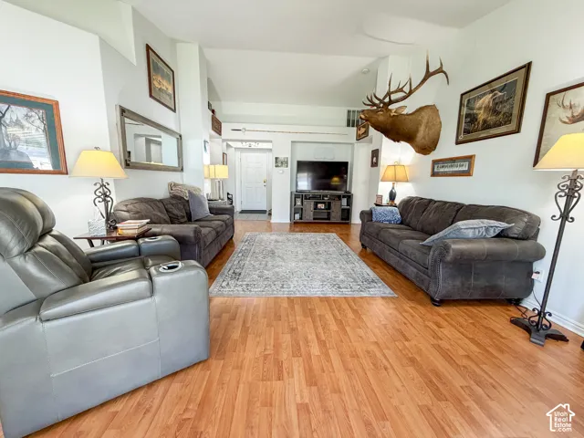 Vaulted ceilings with recessed lighting, wood-finish flooring, and white painted walls