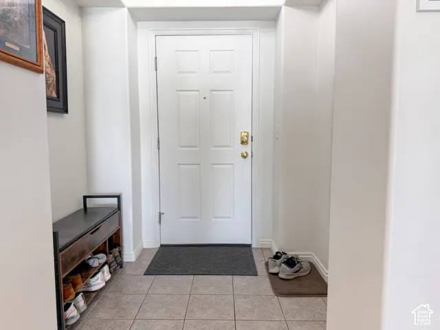 Entryway featuring light-toned tile flooring and a paneled entry door with brass hardware