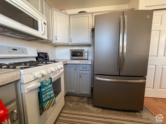 Kitchen featuring gray cabinetry, white subway tile backsplash, a white oven range, and a stainless steel French door refrigerator