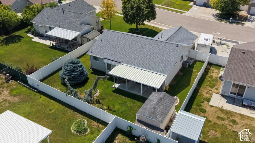 Fenced backyard featuring a covered patio, mature landscaping, and an outbuilding