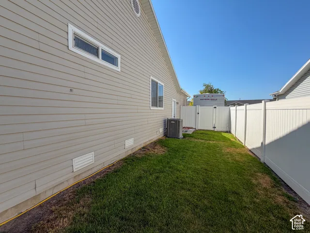 Side yard with a privacy fence, a grass lawn, and light-colored siding