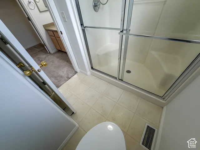 Tile flooring with a walk-in shower featuring a sliding glass door