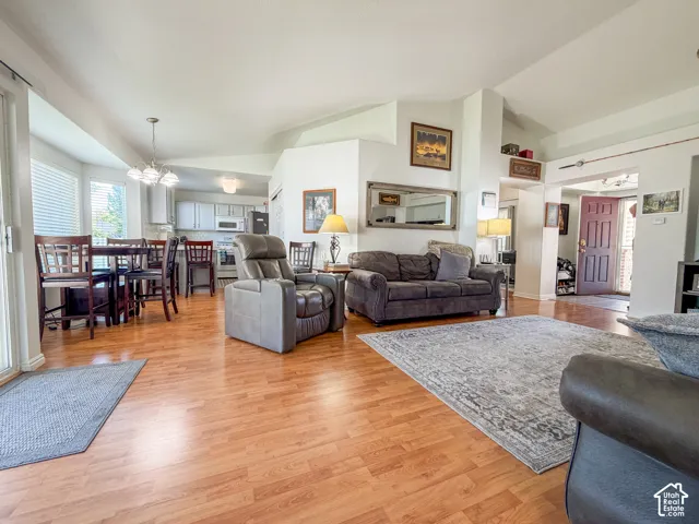 Open concept living space with wood-finish flooring, vaulted ceilings, and a dining area with a multi-light pendant