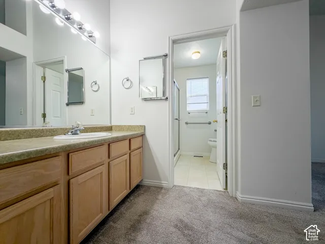 Spacious vanity with light wood-finish cabinetry, solid surface countertop, and large wall-mounted mirror with overhead lighting