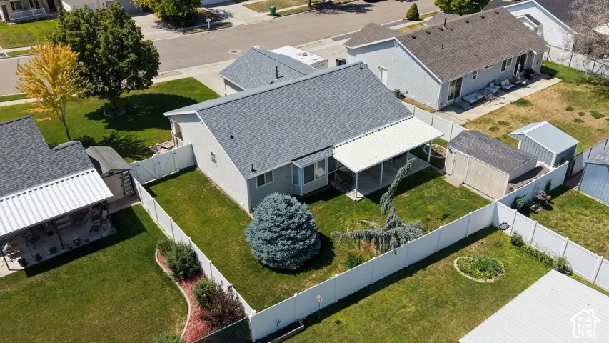 Manicured backyard with a screened-in patio, white privacy fencing, and mature landscaping
