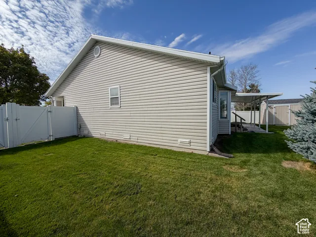 Side yard featuring a vinyl privacy fence, bay window, covered patio, and detached storage shed