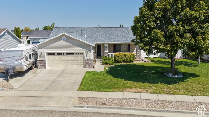 Single-story residence featuring light-colored siding with stone veneer accents, an attached two-car garage, and a concrete driveway