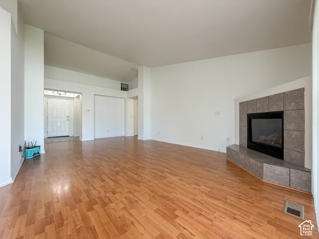 Vaulted ceilings, wood-finish flooring, recessed entry, and a tiled fireplace
