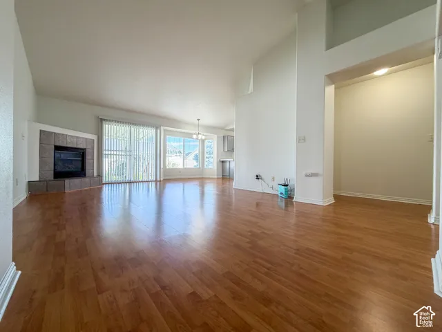 Vaulted ceilings, wood-finish flooring, fireplace with tile surround, sliding glass door, and large windows