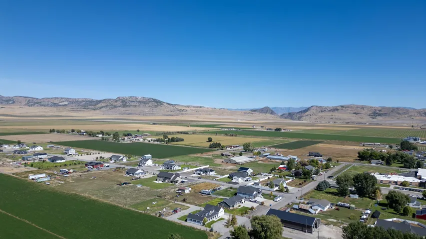 Residential area with established homes, agricultural fields, and distant mountainous terrain