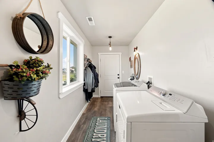 Dedicated laundry area featuring wood-finish flooring, a white paneled door, and a single window with white trim