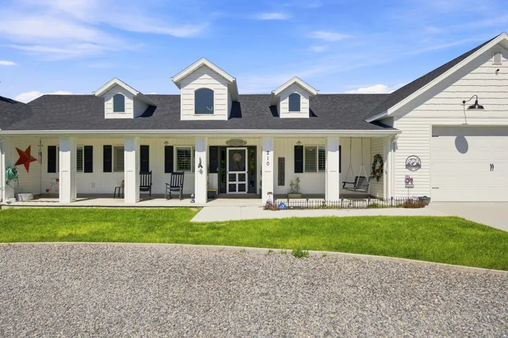 White siding exterior with a dark shingle roof and multiple dormer windows