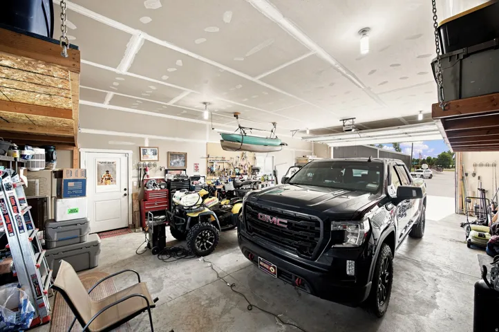 Spacious garage featuring a concrete floor, exposed ceiling joists, and a white entry door