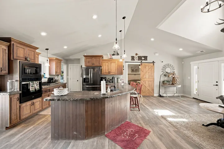 Open-concept living space with vaulted ceilings, wood-finish flooring, and recessed lighting