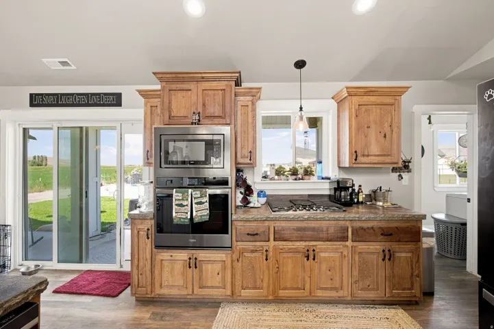 Wood-finish cabinetry with dark hardware, built-in stainless steel microwave and oven, and a gas cooktop