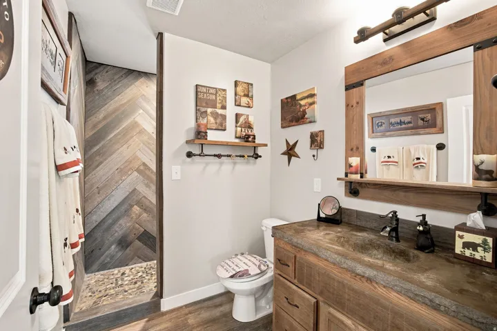 Distressed wood vanity with an integrated sink, framed mirror with shelf, and industrial-style lighting