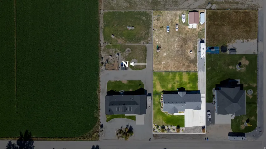 Expansive lot featuring a single-story residence, manicured lawn, a detached storage structure, and a concrete driveway