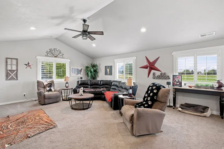 Vaulted ceiling with a ceiling fan, recessed lighting, carpeted flooring, and multiple windows with plantation shutters