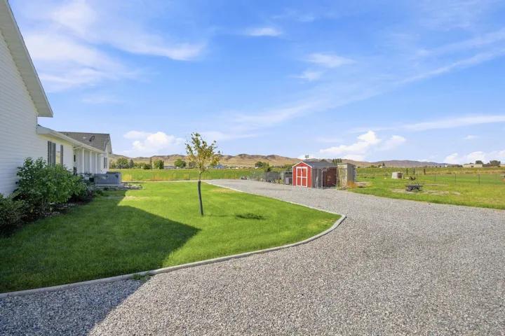 Gravel driveway leading to a white residence with a gabled roof
