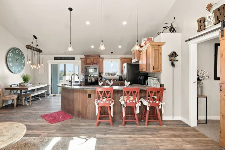 Wood-finish flooring throughout, kitchen island with built-in seating, wood cabinetry, and recessed lighting