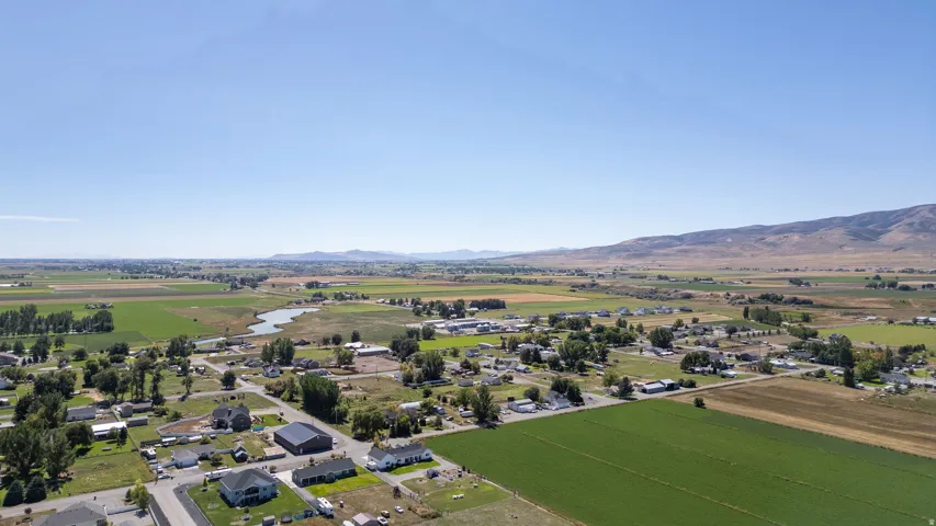 Expansive rural landscape featuring agricultural fields, scattered residential properties, and distant mountains