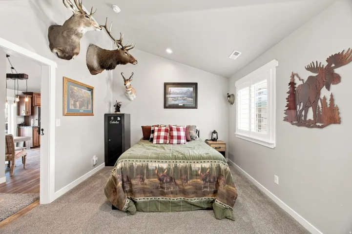 Carpeted room featuring a vaulted ceiling with recessed lighting and a window with plantation shutters