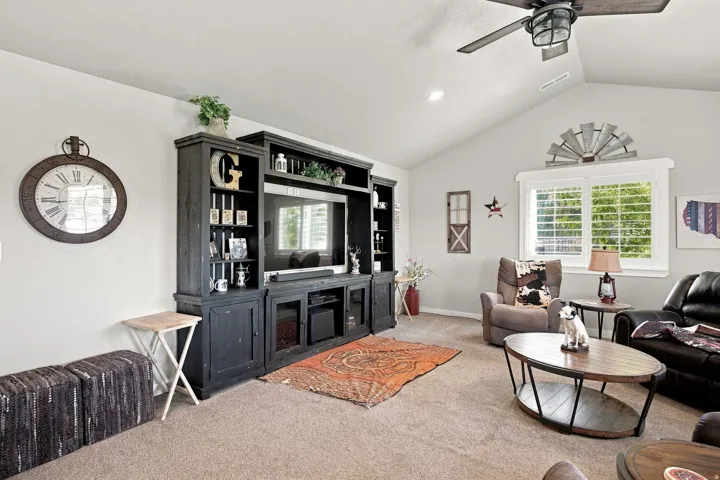 Vaulted ceilings, a built-in entertainment center, recessed lighting, a ceiling fan, and window shutters
