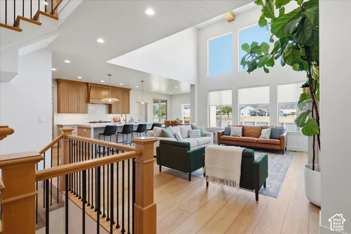 Two-story living area with high ceilings, wood-finish flooring, and multiple large windows