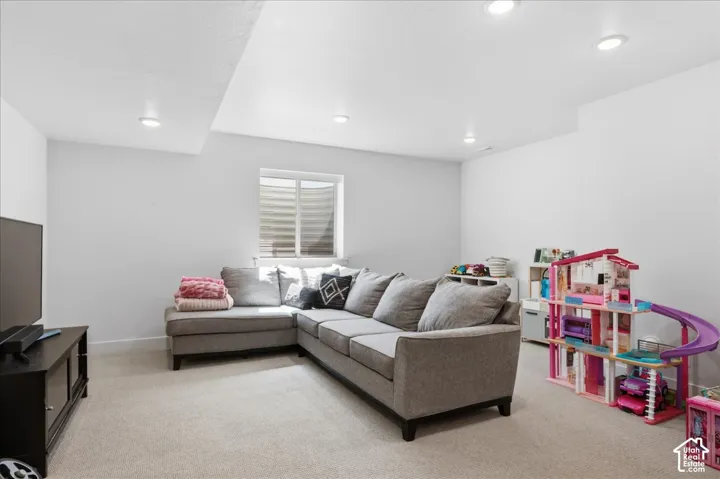 Recessed ceiling lighting, a window with horizontal blinds, and light-toned carpeting