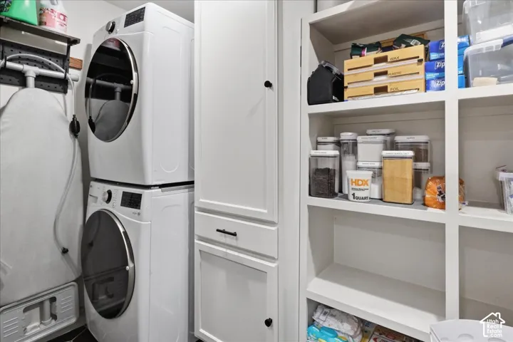 Built-in shelving, vertical paneled cabinetry, and stackable appliances