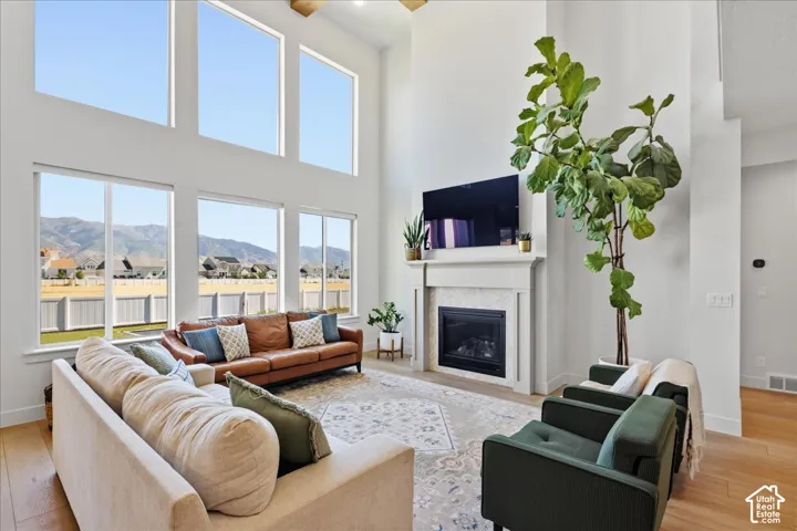 Two-story living area with expansive windows, a gas fireplace with a tiled surround, and light wood-finish flooring
