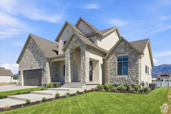 Stucco and stone exterior featuring an arched entryway, gabled rooflines, and an attached garage with a dark wood-finish door