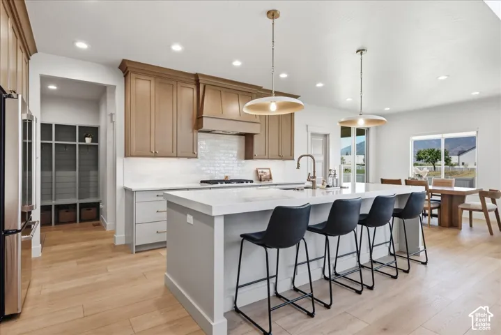 Gourmet kitchen featuring a large central island, light wood-finish flooring, two-tone cabinetry, and recessed lighting