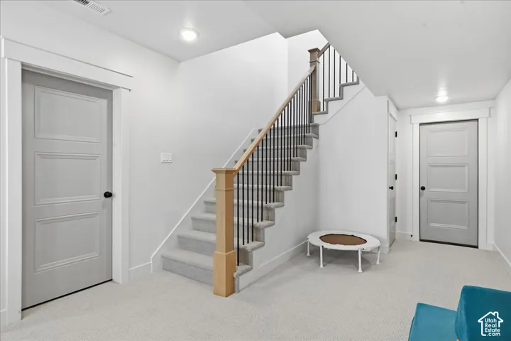 Carpeted staircase with wood newel posts and metal spindles