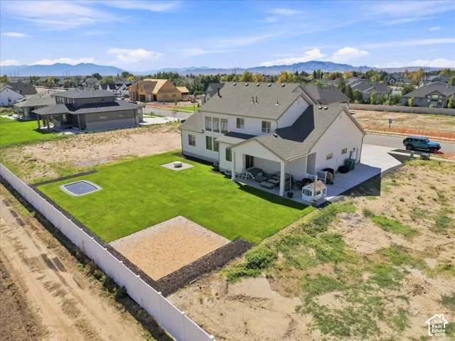 Expansive backyard with a manicured lawn, dedicated gravel area, and white privacy fencing
