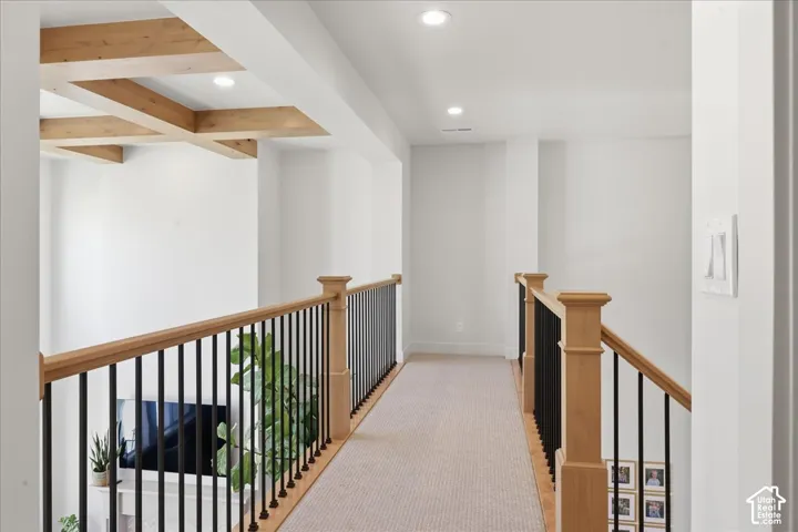 Open landing with light wood-finish railing and black spindles, recessed lighting, and carpeted flooring